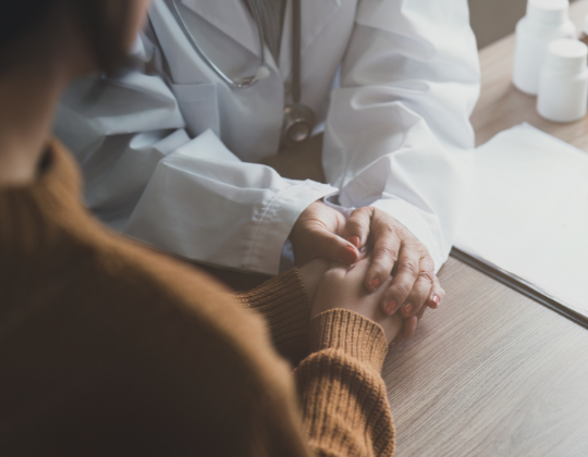 A 45 year old asian doctor with a white coat holding the hands of a patient in a medical office Primary Care Billing Process