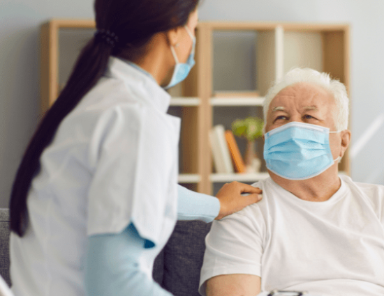 A black haired nurse with brown skin and a surgical mask attending a 70 year old black man with a surgical mask in a living room Medical Credentialing and billing Services