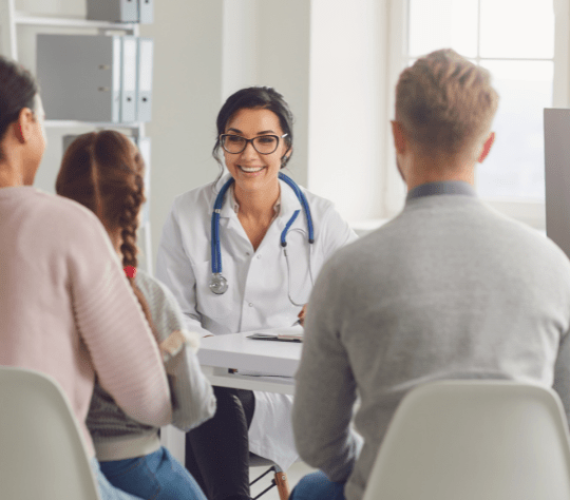 A family of three with an average age of 25 talking with a 35 year old caucasian female doctor with glasses , in a doctor’s office medical front office administration specialist